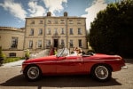 A newly married couple arrive in an open top red car to the Maryborough Hotel after their wedding ceremony 